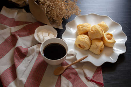 Tasty mini sausage in bread rolls and Cup of hot coffee on dark background