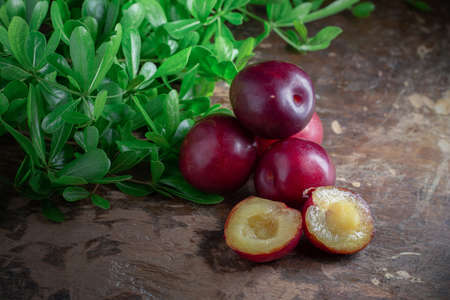 Red cherry plum with green leaves on wooden backgroundの写真素材