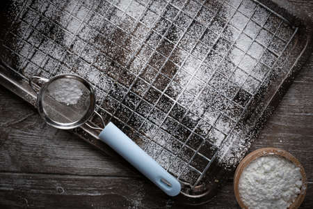 A metal grate on old wooden table background. Bread equipment concept.