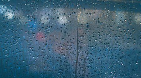 raindrops on the window of the car. Abstract blur bokeh of traffic and car light.