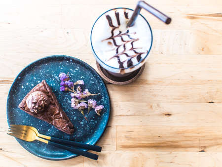 chocolate cake with little flower decorate dish on wooden table dessert idea with iced chocolateの写真素材
