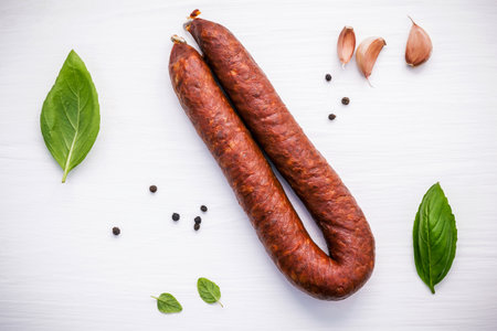 Chorizo sarta smoked sausage with basil leaves ,black pepper ,garlic and oregano on white wooden background.の写真素材