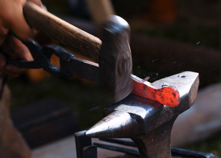 Traditional style blacksmith at work. Hammer hands and iron.