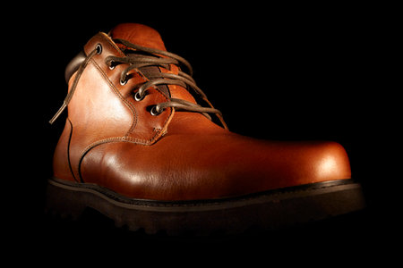 Men's winter brown shoes on black background. Low angle close shot.