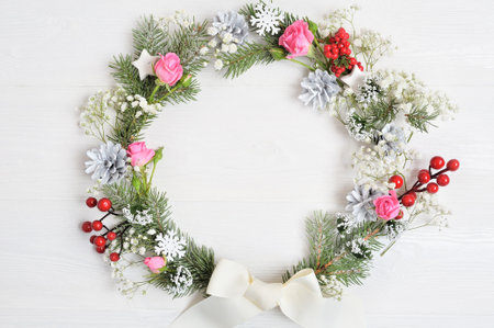 Mockup of Christmas Wreath Made of Naturalistic Looking Pine Branches Decorated with Red Berries. Flat lay on a white wooden background, with place for your text. Top view.の写真素材