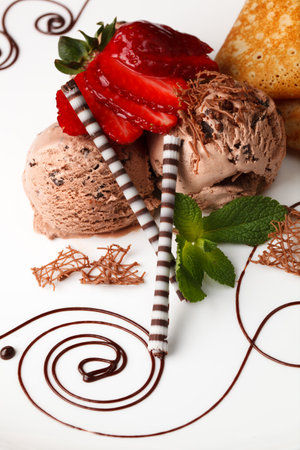 Chocolate ice cream topped with fresh strawberries and served with decorative striped chocolate straws and a sprig of mintの写真素材
