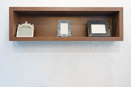Empty photo frame on wooden shelf with white wall backgroundの写真素材