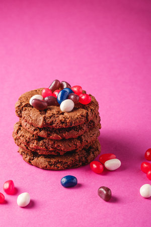 Homemade oat chocolate cookies stack with cereal with juicy jelly beans on minimal pink purple...