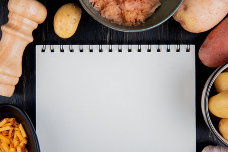 top view of whole grated and fried potatoes around note pad with salt on wooden background with copy spaceの写真素材