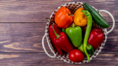 top view of vegetables as cucumber pepper tomato in basket on wooden background with copy spaceの写真素材