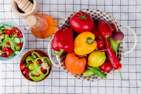 top view of vegetables as pepper tomato cucumber in basket with vegetable salad melted butter and garlic crusher on plaid cloth backgroundの写真素材