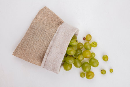 top view of white grape berries spilling out of sack on white backgroundの写真素材