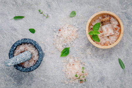 Himalayan pink salt in wooden bowl with peppermint ,sage,thyme,basil and oregano on stone background. Himalayan salt commonly used in cooking and for bath products such as bath salts...の写真素材