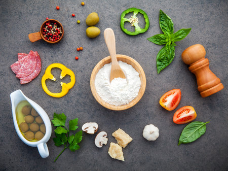 The ingredients for homemade pizza with herbs flat lay on dark stone background.の写真素材