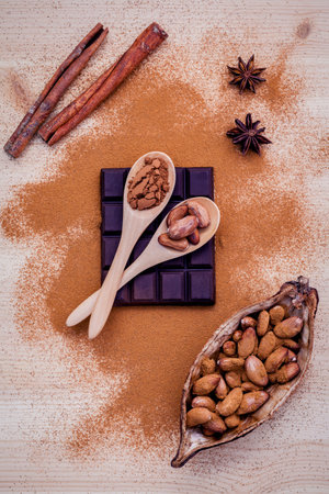 Brown chocolate powder in spoon , Roasted cocoa beans in the dry cocoa pod fruit and dark chocolate setup on wooden background.の写真素材