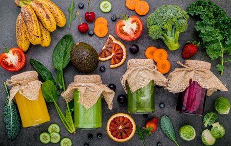 Colourful healthy smoothies and juices in bottles with fresh tropical fruit and superfoods on dark stone background with copy space.の写真素材