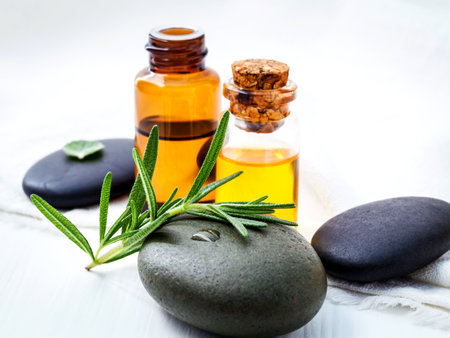 Fresh rosemary and fresh peppermint on spa stone with essential oil setup on white wooden table. Selective focus shallow depth of field.の写真素材
