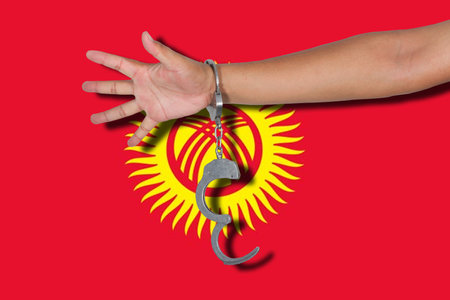 handcuffs with hand on Kyrgyzstan flagの写真素材