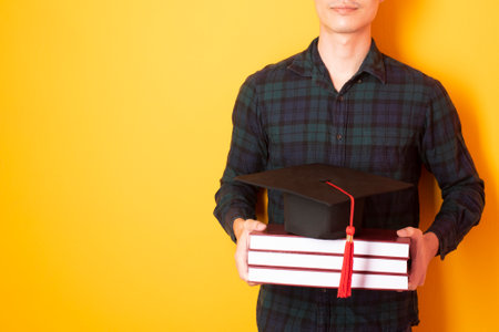 University man is happy with graduation on yellow backgroundの写真素材