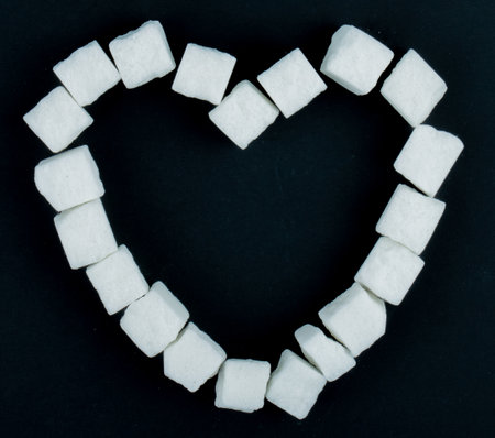 top view of sugar cubes arranged in a shape of a heart on black backgroundの写真素材