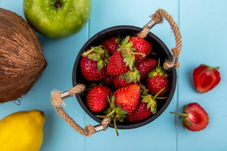 top view of strawberry on a basket with slices of strawberry with coconut on a blue backgroundの写真素材