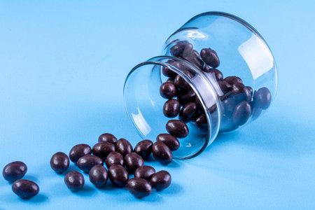side view chocolate candies in a glass jar on a blue backgroundの写真素材