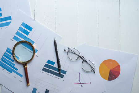Magnifying glass and documents with analytics data lying on table,selective focusの写真素材