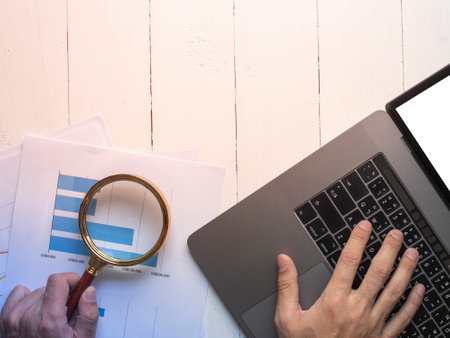 Magnifying glass and documents with analytics data lying on table,selective focus
