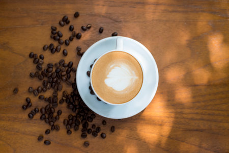 Coffee cup and coffee beans on table on a wooden deskの写真素材