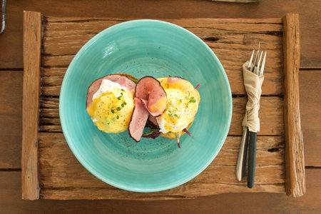 Eggs Benedict on wooden plate background