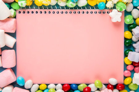 top view of pink sketchbook and candies in multi-colored glaze scattered aroundの写真素材
