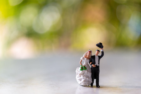 Miniature people : Bride and groom outdoors with green bokeh background and copy space for text , Happy valentine's day conceptの写真素材