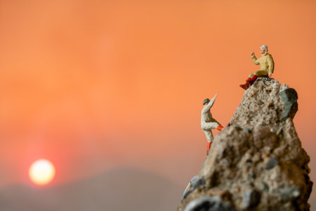 Miniature people: Hikers climbing up on the rock . Sport and leisure concept.