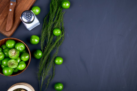 top view of a wooden cutting board with a knife , salt shaker, dried peppermint in a mortar, fennel...