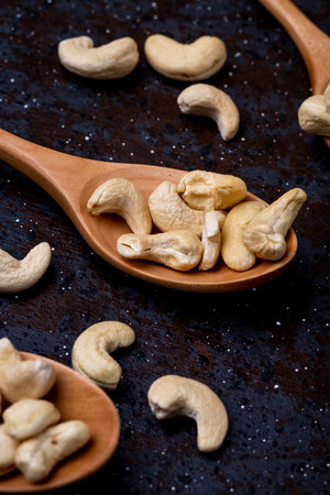 side view of wooden spoons with salted roasted pistachios on black backgroundの写真素材