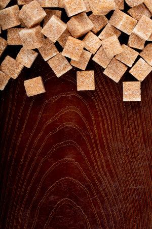 top view of brown sugar cubes scattered on wooden background with copy spaceの写真素材