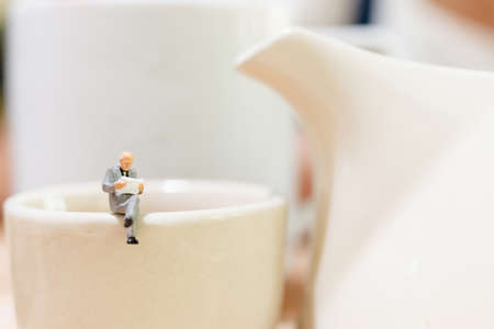Miniature people : businessman and woman sitting on a cup of teaの写真素材
