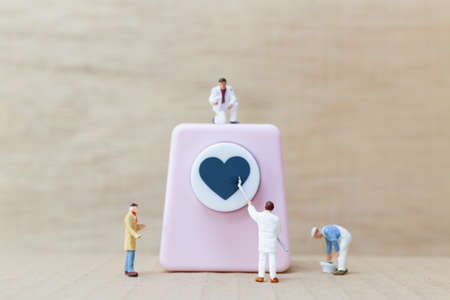 Miniature people painting Heart shaped punching machine with copy spaces for your textの写真素材