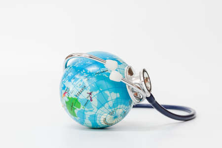 Stethoscope wrapped around globe on white background.の写真素材