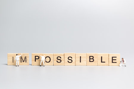 Miniature people worker team on impossible word in wooden alphabet lettersの写真素材