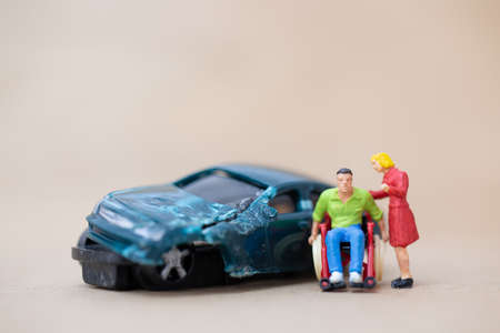 Miniature people : Disabled man sitting in wheelchair on on wooden backgroundの写真素材