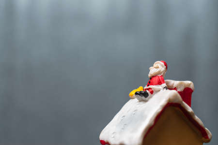Merry Christmas and happy holidays! Cute Santa Claus sitting on the roofの写真素材
