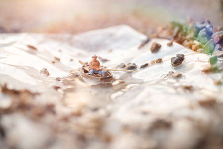 Miniature fishermen are fishing by boatの写真素材