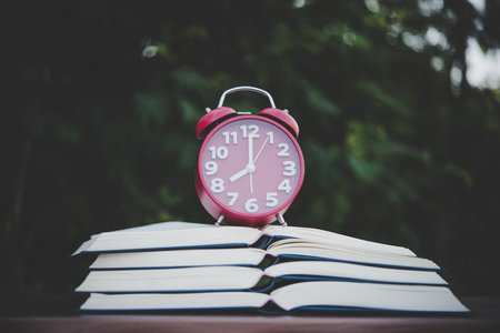 alarm clock and books on the wood table with bokeh background.の写真素材