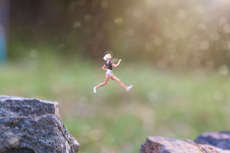 Miniature people : Running on rock cliff with nature background