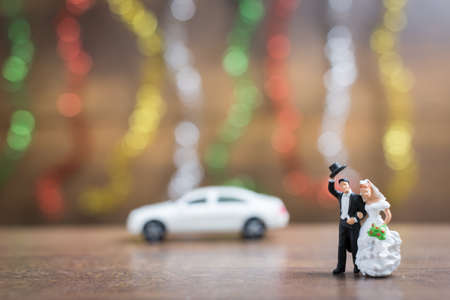 Miniature people bride and groom on wooden floor with colorful bokeh backgroundの写真素材