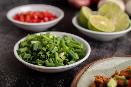 Chopped scallions in a cup over black cement. Selective focus.の写真素材