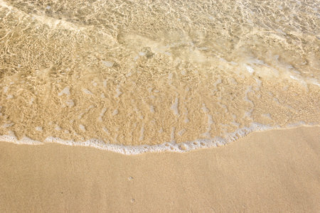 Soft waves with foam of ocean on the sandy beach background