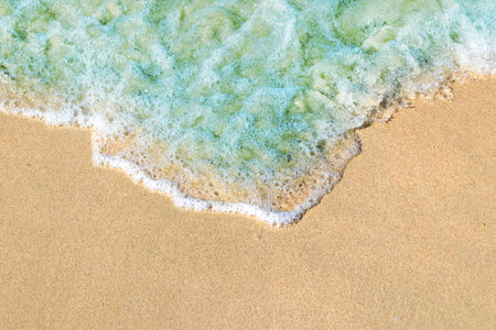 Soft waves with foam of blue ocean on the sandy beach
