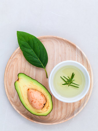 Alternative health care fresh avocado , leaves and oil on marble background.